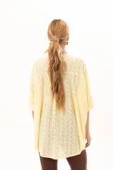 Camisa de corte oversize y mangas murciélago, confeccionada en tela con perforaciones tipo broderie. Presenta cuello mao, cierre frontal con botones y un diseño holgado y fluido.