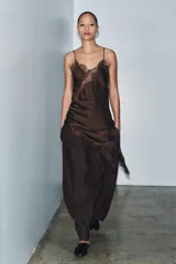 Pantalón marrón de tiro medio y corte carrot wide leg. Presenta trabillas en la cintura, bolsillos laterales ocultos en la costura, pespuntes marcados a tono y una hebilla decorativa en la espalda. Cierre frontal con cremallera, botón y ganchos metálicos.