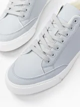 Championes urbanos de diseño minimalista en color beige, con suela de goma blanca y detalles en color marrón en el interior y borde del cuello.