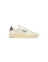 Championes Autry modelo Dallas Low de cuero en color blanco con suela de goma en tono crema. Presenta detalle de parche con logo de la marca y bandera estadounidense en el lateral, y refuerzo en el talón en color marrón oscuro.
