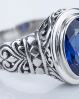 Anillo de plata 925 con diseño calado y piedra facetada azul en forma ovalada.
