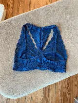 Soutien tipo bralette negro de encaje con diseño floral, espalda estilo nadador y elástico en el bajo busto para sujeción.