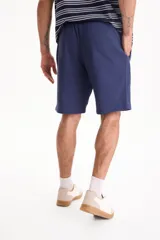 Bermuda deportiva sin friza color azul marino, con cintura elástica con cordón ajustable y bolsillos laterales.