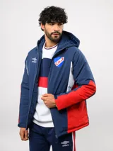 Campera de abrigo Umbro del Club Nacional de Football, con diseño de bloques de color en azul, blanco y rojo. Cuenta con capucha ajustable, cierre frontal y logo de la marca junto al escudo del club en el pecho.