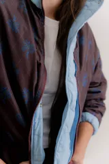 Campera reversible de estilo parka, color celeste, con diseño capitoneado con patrón de flores. Presenta ajuste elástico en la cintura, cuello alto y mangas largas. Incluye parche de marca en la parte superior de la espalda.