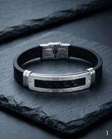Pulsera de diseño moderno con estructura central de acero inoxidable y laterales de goma negra. Presenta un detalle central con el patrón de guarda griega grabado sobre fondo negro.