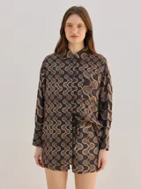 Camisa de algodón con estampado geométrico de ondas en tonos marrón y negro, corte holgado, mangas largas y cuello clásico.