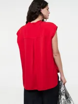 Camisa roja sin mangas con cuello mao, cierre frontal de botones y dos bolsillos funcionales en el pecho.