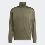 Conjunto deportivo Adidas compuesto por campera con cierre frontal y pantalón largo, ambos en color verde oliva. La campera presenta cuello alto y el pantalón cuenta con cintura elástica ajustable. Ambos incluyen bolsillos laterales y el logo de la marca estampado en tono oscuro.