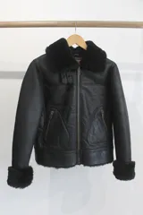 Campera de cuero genuino color negro, con cuello y puños de corderito sintético, cierre frontal y bolsillos laterales con cierre.