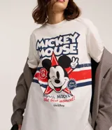 Remera blanca de algodón con estampado gráfico de Mickey Mouse en el centro, rodeado de estrellas y franjas rojas y azules. Incluye el texto "MICKEY MOUSE" en la parte superior.