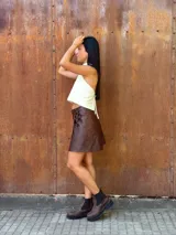 Minifalda tipo pareo confeccionada en cuero color chocolate, con diseño cruzado y cierre mediante tiritas laterales ajustables.