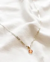 Collar plateado con cadena de eslabones y dije circular color durazno.