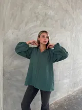 Camisa de color verde petróleo con cuello camisero, mangas largas abullonadas y detalles de bordado floral en las mangas y el frente.