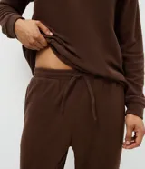 Pijama masculino de dos piezas confeccionado en tejido fleece texturizado. Incluye una remera de manga larga con cuello redondo y puños ajustados, y un pantalón tipo jogger con cintura elástica, cordón de ajuste y bolsillos laterales.