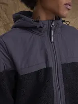 Campera con capucha confeccionada en una combinación de tejido técnico y sherpa, con cierre frontal completo y puños elásticos.