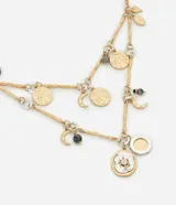 Collar de capas en metal reciclado con baño mixto (dorado y plateado). Presenta cadenas finas y retorcidas con dijes fijos, incluyendo lunas, monedas texturizadas y dijes redondos con detalles de cristal.