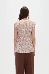 Blusa de poliéster sin mangas con cuello redondo y estampado geométrico en tonos marrones y blancos, de corte holgado y diseño fluido.