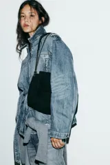 Bolso de hombro confeccionado en piel de gamuza color marrón, con diseño estructurado y pespuntes decorativos en la solapa. Cuenta con una correa de cadena metálica dorada con refuerzo de piel y cierre imantado.