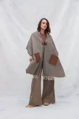 Chal de lana fina sin teñir con diseño de cuadros sutiles, cierre frontal con alamar y bolsillos de cuero metalizado. Presenta terminaciones con flecos en el ruedo y un calce estructurado en los hombros.