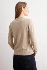 Cardigan de punto color tostado, con escote redondo, manga larga y cierre frontal de botones a tono.