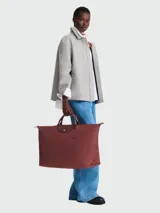 Bolso de viaje tipo shopper Longchamp modelo Le Pliage Green XL, color rojo oscuro/terracota, con asas y solapa de cuero marrón.