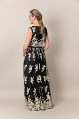 Vestido largo de tul negro con bordado dorado de flores. Tiene escote en V cruzado, sin mangas y falda amplia.