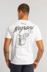 Camiseta blanca de manga corta con estampado gráfico en la espalda que ilustra un cóctel Negroni con texto descriptivo.