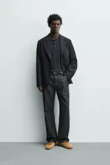 Blazer relaxed fit de estructura color gris, confeccionado en tejido con algodón, cuello con solapas de muesca, manga larga con botones en los puños y bolsillos de plastrón en la cadera.