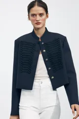 Pantalón de jean blanco de tiro alto y corte wide leg, con bolsillos delanteros y traseros. Cierre frontal con cremallera y botón metálico.