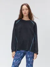 Remera de manga larga MUTMA Sticha, color negro con efecto acid wash y costuras decorativas expuestas en color celeste brillante. Cuenta con corte clásico, cuello redondo a la base y calce holgado.