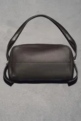 Bolso alargado de piel color marrón oscuro, con asa de hombro y cierre de cremallera. Incluye cartera con bolsillo extraíble.