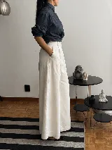 Pantalón de tiro alto con corte wide leg y caída fluida. Presenta bolsillos laterales y cierre frontal, confeccionado en lino natural.
