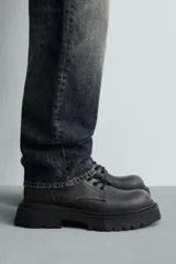 Bota tipo derby con cordones, confeccionada con acabado efecto desgastado. Presenta horma redonda y suela gruesa con diseño track.