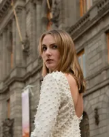 Top corto color crema, de manga media, con espalda baja y cuello bateau confeccionado en tela stretch. Textura de perlas salpicadas aplicadas a mano.