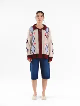 Campera tejida en jacquard con cierre frontal, cuello tipo polo y bolsillos delanteros. Diseño multicolor con estampado geométrico de rombos y detalles bordados a mano.