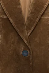 Chaqueta larga de piel color marrón, con cuello solapa, manga larga, bolsillos delanteros de plastrón y cierre frontal con botones.