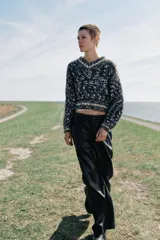 Pantalón de tiro alto con diseño de pierna ancha, confeccionado en tejido efecto piel. Cuenta con bolsillos delanteros, falsos bolsillos traseros de vivo y cierre frontal con cremallera y ganchos metálicos.