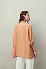 Camisa estampada con figuras geométricas en tonos azul, marrón y beige. Corte relajado, manga tres cuartos y botones al frente.