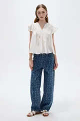 Blusa de algodón blanca con cuello en V, frunces frontales y mangas cortas con volados.
