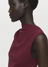 Vestido midi color bordó, con cuello redondo alto, diseño sin mangas, fruncido lateral y corte entallado.