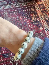 Anillo elástico de cuentas redondas de piedra dálmata con una cuenta dorada.