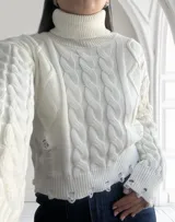 Sweater blanco de tejido de punto trenzado con cuello alto y terminaciones desflecadas.