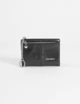 Billetera plegable de cuero vegano color negro, con cierre superior para monedas y cadena lateral con argolla metálica. Incluye logo metálico de la marca en el frente.