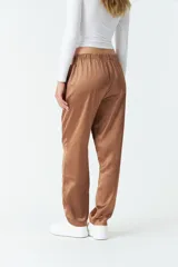 Pantalón de vestir color marrón satinado, de tiro medio, corte recto y con bolsillos laterales.