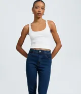 Pantalón skinny de tiro alto confeccionado en denim azul oscuro. Presenta un diseño clásico con cierre de cremallera y botón, trabillas para cinturón y bolsillos funcionales tanto en la parte delantera como en la trasera.