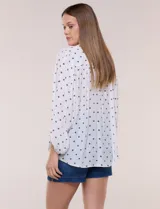 Blusa holgada de gasa texturizada color blanco con estampado de lunares negros, escote en V con botones frontales, mangas 3/4 abullonadas y puños elásticos.