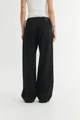 Pantalón de jean negro, de corte holgado desde la cadera hasta el bajo, con tiro medio y cierre frontal con botones.