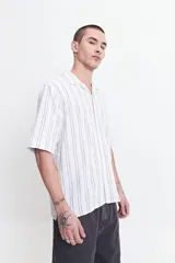 Camisa de manga corta a rayas verticales blancas y grises, con cuello camisero y corte recto. El modelo usa talle M.