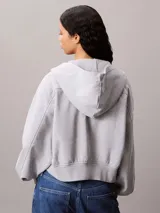 Buzo con capucha y cierre frontal completo, confeccionado en felpa francesa de algodón. Presenta un diseño de corte holgado con mangas amplias, puños y dobladillo en punto canalé, y el logo de la marca aplicado en el pecho.